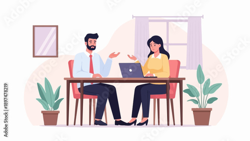 Two professionals in office attire are seated at a desk, discussing work over a laptop