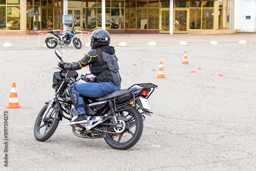 Rider practices motorcycle skills in an outdoor training area during a sunny afternoon
