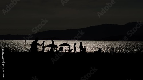 Backlit beach sunset with people silhouettes along the shoreline