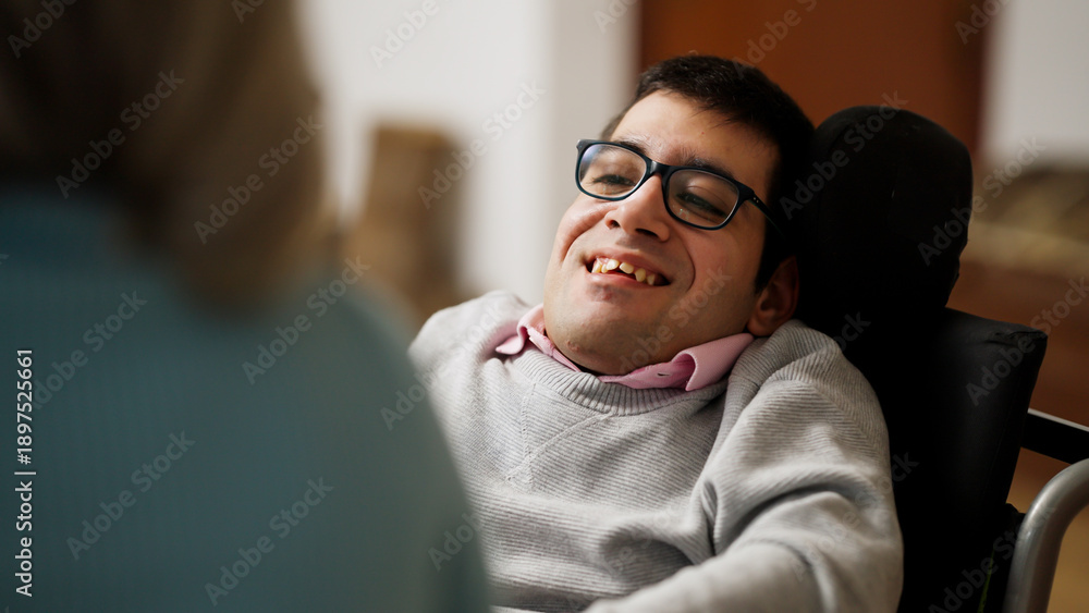 Fototapeta premium Man with physical disability in a wheelchair smiling, engaging in a conversation at home, fostering inclusion and positive well being