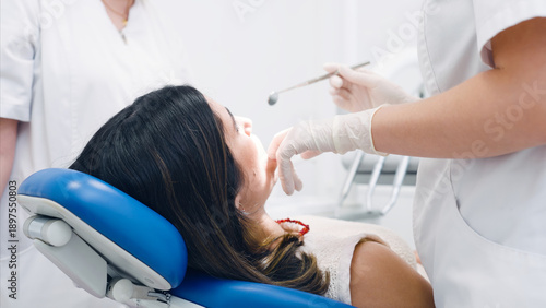 Fotografie Dentist in protective gloves checking a patient's mouth with dental tools during