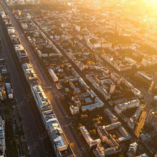 Breathtaking aerial view of a sprawling city at sunset. Warm golden hour light illuminates residential blocks and long roads, perfect for urban planning, real estate, or travel marketing.