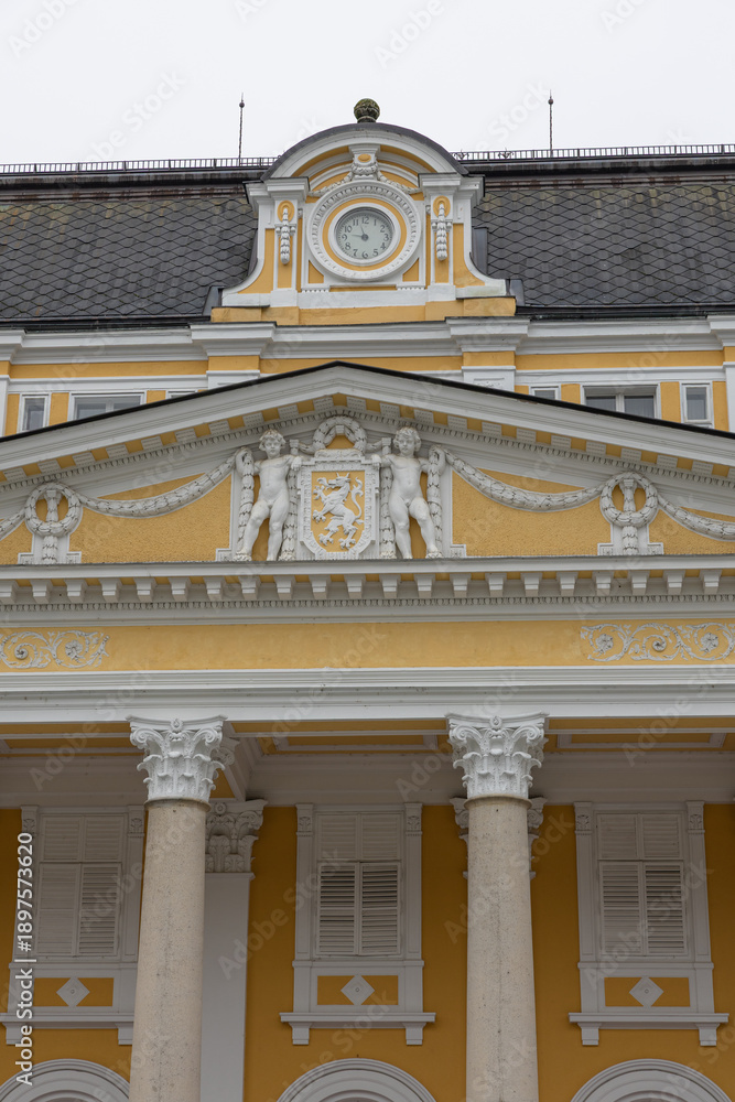 Obraz premium Yellow Historic Building Facade With Clock, White Sculptures And Classical Columns