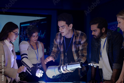Robotics engineers in an RD lab test an AI powered prosthetic arm. The diverse team, including an Indian woman, analyzes the bionic prototype's hardware and design at night.