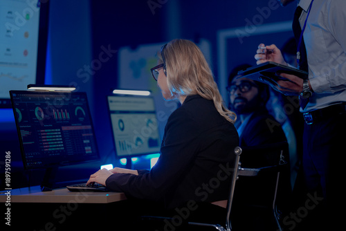 Photography Professional female analyst monitoring business data on multiple computer screens