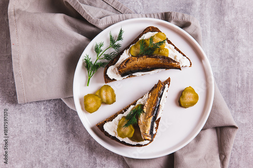 Fotografie Close up of sandwiches with ricotta, pickles and sprats on rye bread on a plate