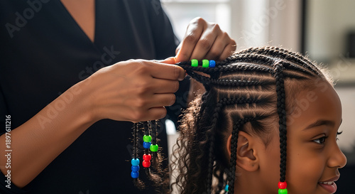 Mother braiding daughter's hair with colorful beads in home setting  