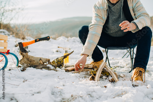 Person preparing campfire in snow for outdoor activity