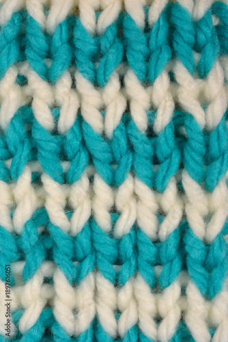 A close up shot shows a thick wool knit pattern featuring alternating horizontal stripes of white and turquoise blue yarn.