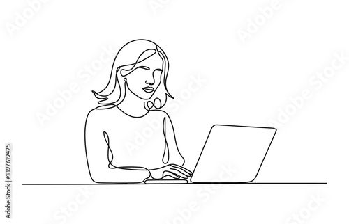 A woman works on her laptop with a focused expression in a minimalist setting.