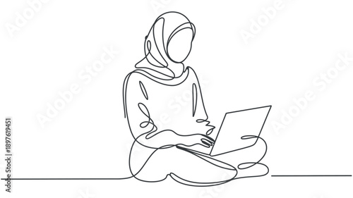 A woman wearing a hijab sits cross-legged on the floor with a laptop in a minimalist setting.