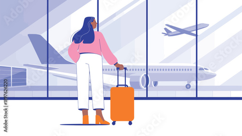A woman with a suitcase stands in an airport terminal looking out the window at a plane taking off