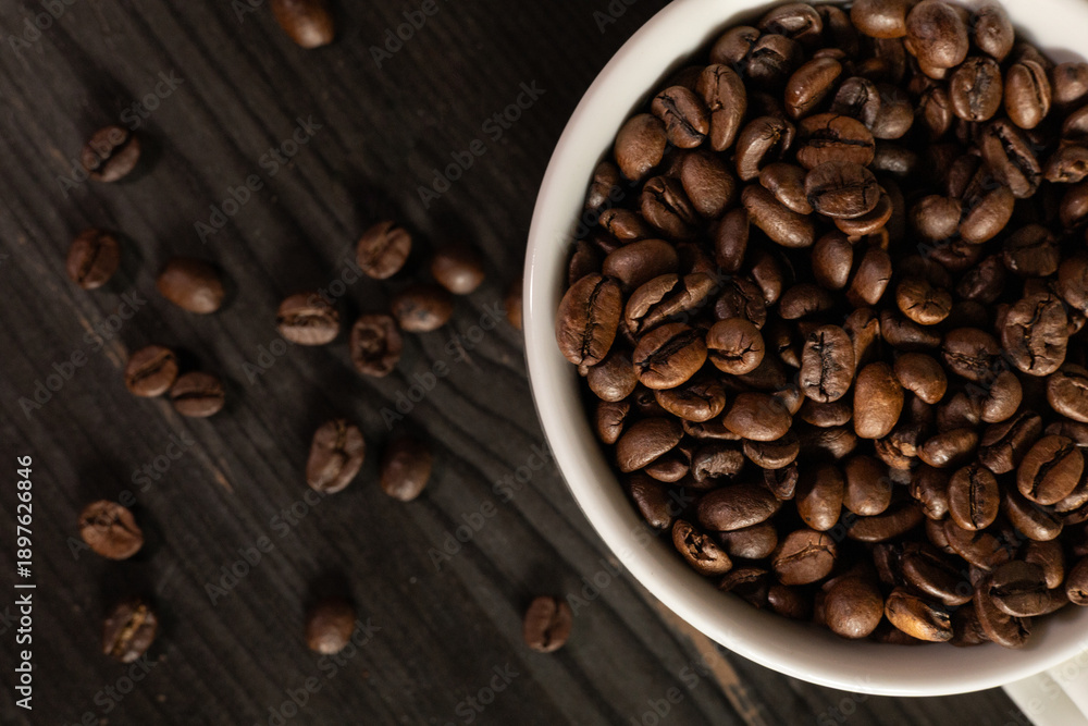 Fototapeta premium White coffee cup filled with coffee beans, minimal still life, clean background, coffee concept.