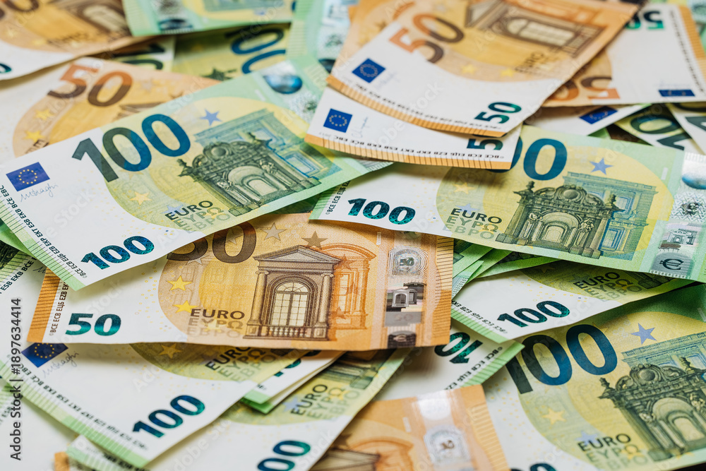 Obraz premium Close-up view of assorted Euro banknotes in denominations of 50 and 100 euros spread out on a flat surface, showcasing intricate designs and colors
