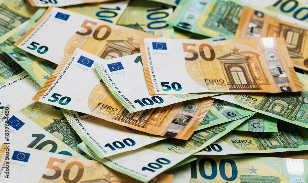 Obraz premium Close-up view of assorted Euro banknotes including 50 and 100 denominations arranged on a flat surface, showcasing detailed designs and colors of currency
