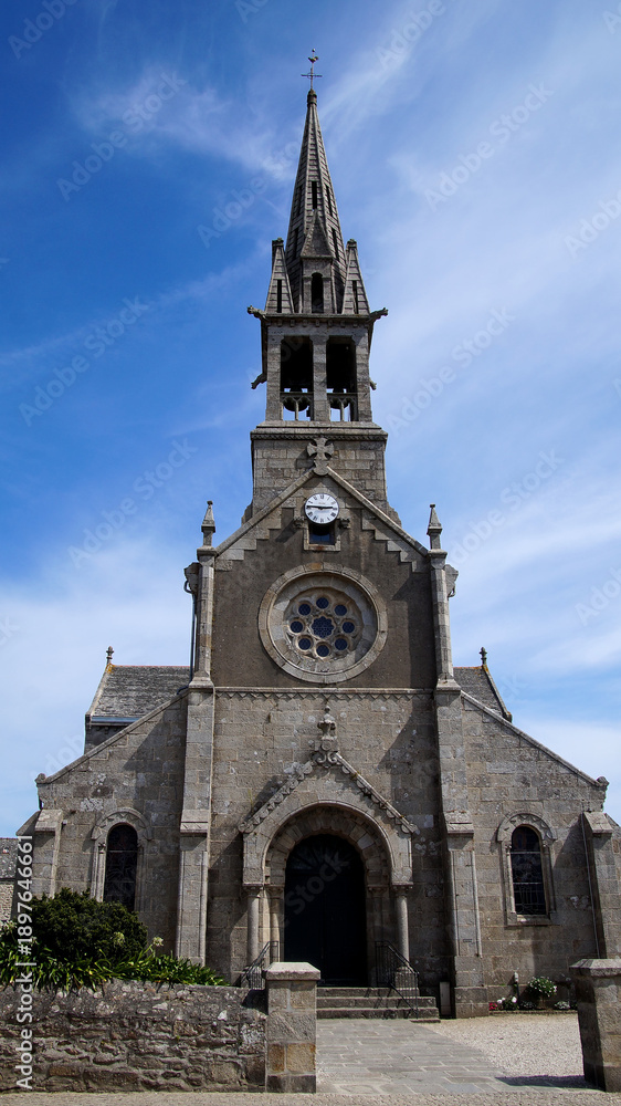 Fototapeta premium Frontal view of a church with a distinctive tower and entrance under a blue sky, showcasing symmetrical historical architecture.