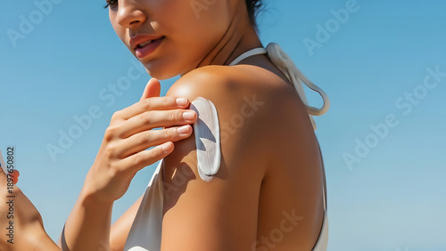 Woman applying sunscreen on shoulder on sunny day