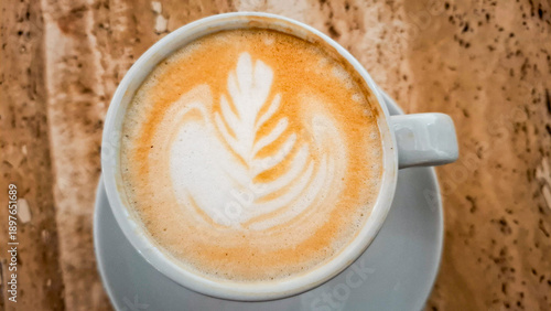 Cup of Cappuccino with Latte Art on Marble Table, Top View. Warm and aromatic coffee drink served in a white cup, ideal for cozy cafe and morning lifestyle concepts.
