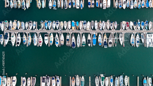 Photos Top down aerial view of boats docked side by side in a marina creating a repeating pattern over dark blue water