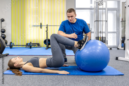 Foto Doctor assists patient with stability ball exercise in rehab center