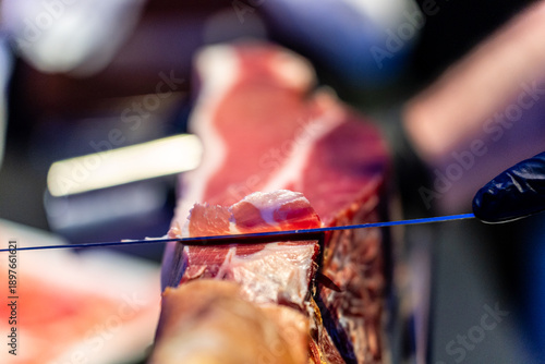 Hand slicing thin iberico ham for spanish charcuterie