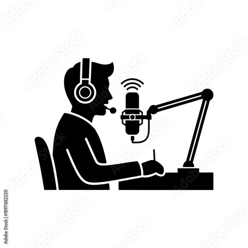 Man wearing headphones speaking into a microphone at a desk.