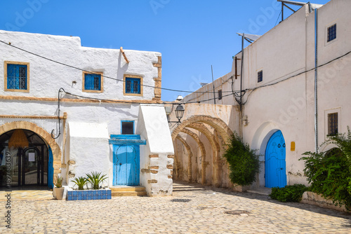 A traditional white house with a blue door in the capital of Djerba Island, Houmt Souk, Tunisia.