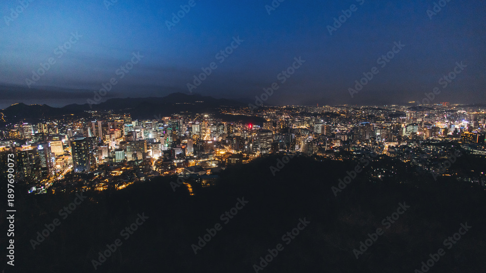 Naklejka premium Seoul night skyline, South Korea, beautiful aerial twilight view, with mountains and scenery beyond the city, seen from observation deck of Namsan Park, Gyeonggi-do province, Republic of Korea