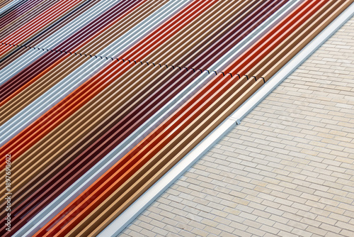 Tableau sur toile High-angle view of colorful metal louvres and pale brick wall forming bold diagonal stripes