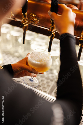 Fényképezés Fresh draft beer being poured from taps into a glass
Golden lager served from a