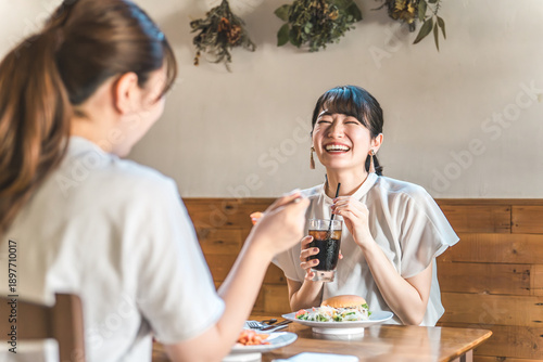 Tableau sur toile Young Asian women chatting while having lunch in a cafe/restaurant