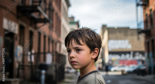 A young boy stands alone on a city street with a blurred background