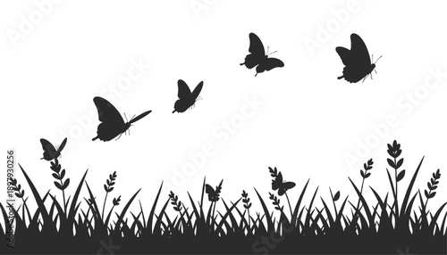 Black butterfly silhouettes flying above fresh spring meadow grass and wild plants creating a simple seasonal nature background