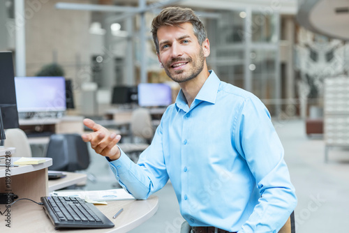 Businessman sitting at his desk in the office and smiling looking at camera