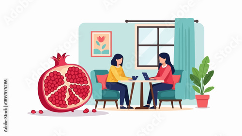 Two women sit at a table with laptops, a pomegranate sits to the left