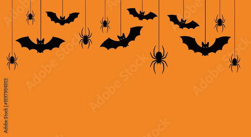 Flat lay of hanging black bat and spider silhouettes on orange background for Halloween