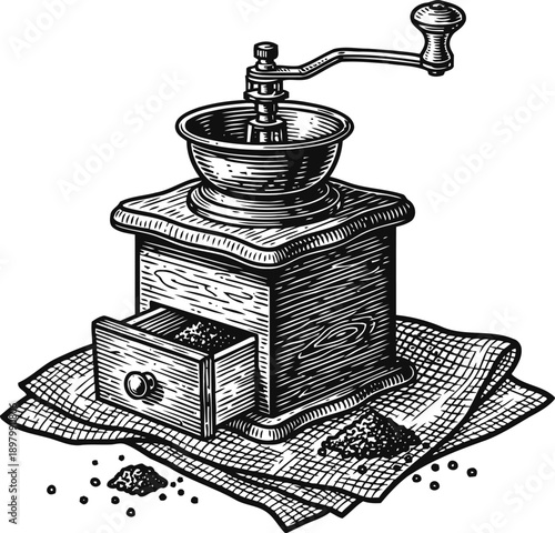 Vintage manual coffee grinder with wooden drawer and scattered coffee grounds on cloth