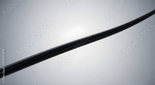Black wire or cable on gray gradient background with soft lighting and subtle shadows
