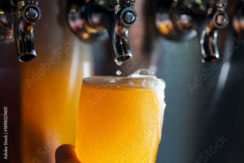 Canvas Print Overflowing glass of beer just poured from tap