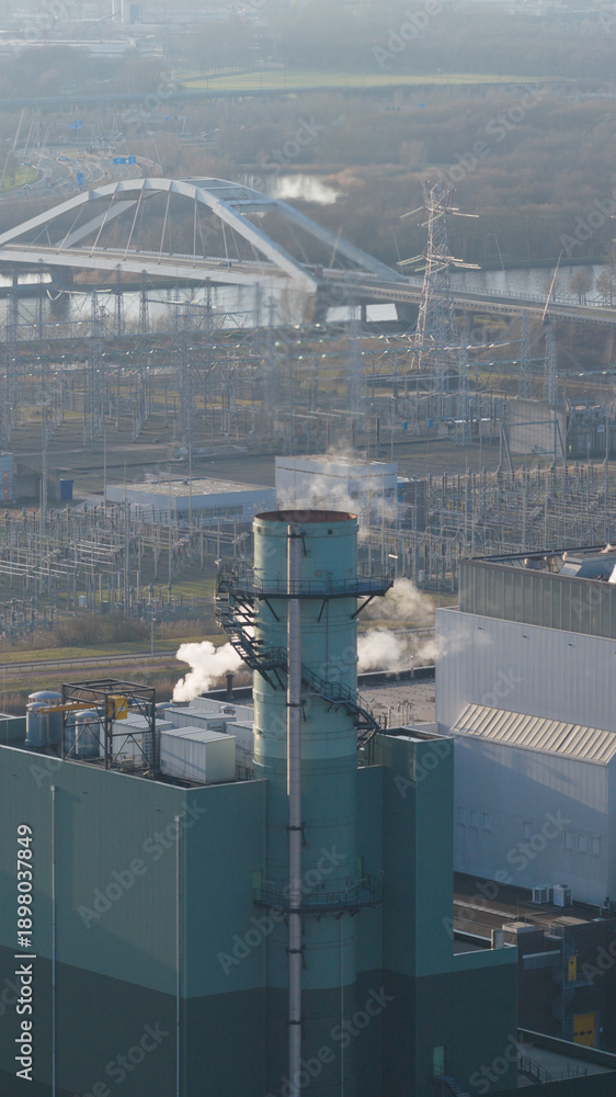 Obraz premium Industrial power plant generating steam with urban infrastructure