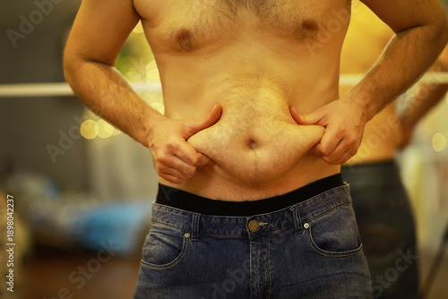 Schilderij op canvas Man Grabbing Belly Fat, Focusing on Weight Loss and Body Image Concerns