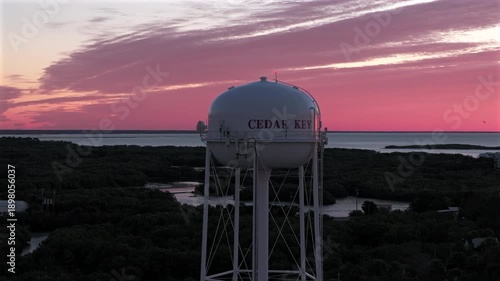 Iconic Cedar Key fishing village water tower standing tall against a breathtaking pink and gold sunrise on 