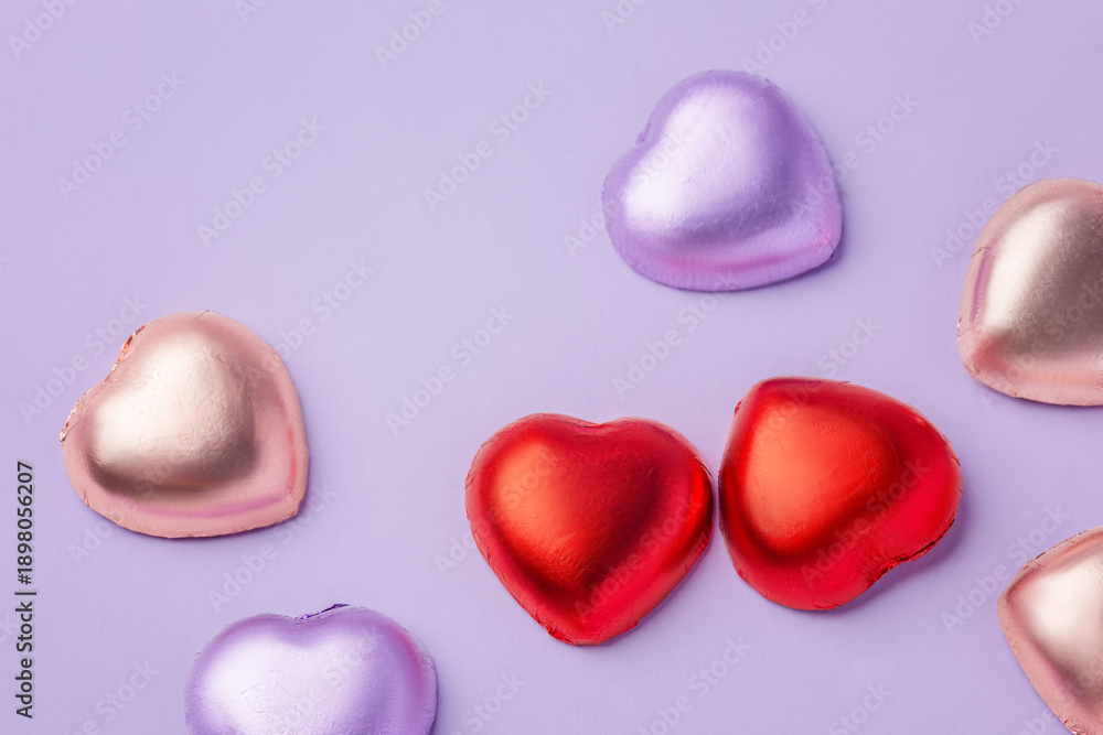 Fototapeta premium Heart chocolate with colorful foil wrapped on purple background, valentines day and love concept