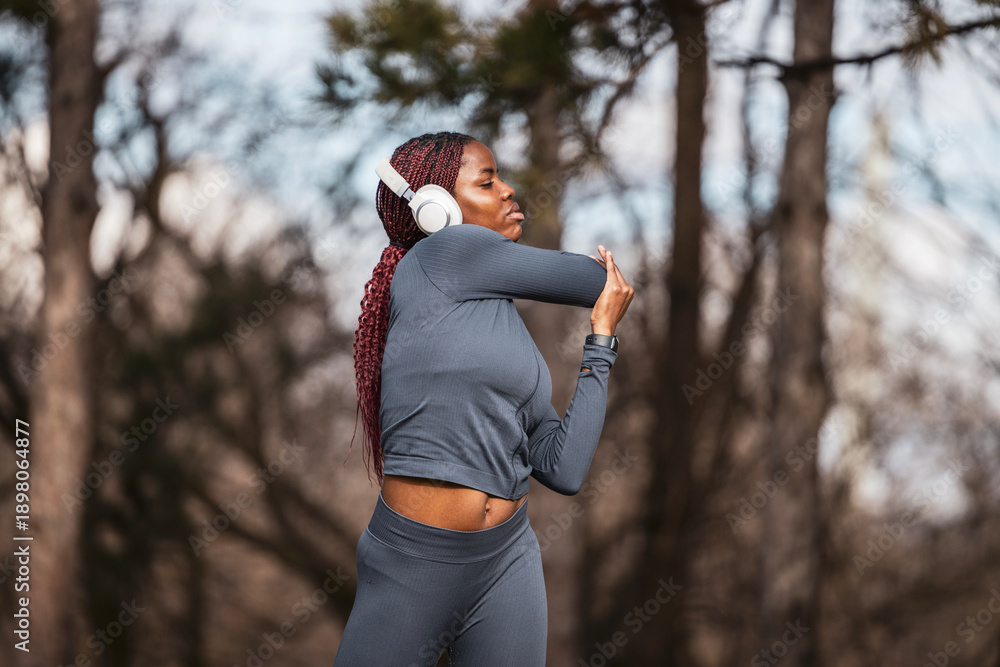 Naklejka premium Black woman stretching arm warming up for outdoor running