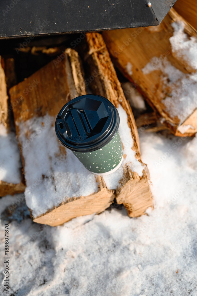 Φωτογραφία Cup of coffee on snow near firewood, cozy winter leisure concept with outdoor warmth, relaxation and cold season atmosphere