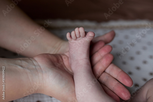 A tender family moment at home: the mother carefully holds the baby's little legs. An atmosphere of love, care and closeness between mother and child. The concept of motherhood, early childhood