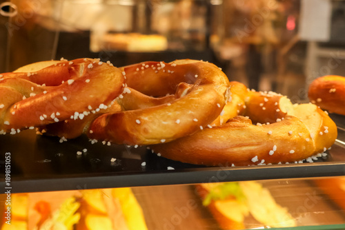 Slika na platnu Close up of golden brown pretzels sprinkled with salt granules, ready for sale i