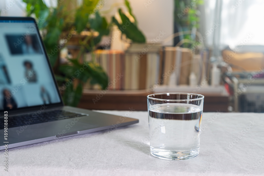 Φωτογραφία A glass of water and open laptop during business meeting, on the table lined with white linen