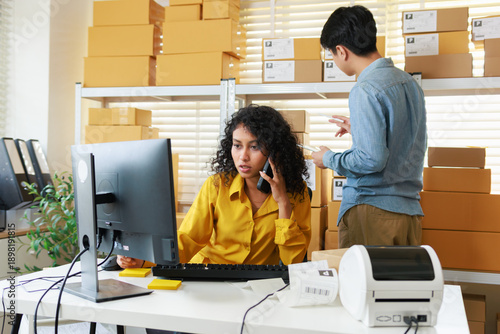 Foto Female Small Business owner, warehouse stock manager Reviewing Order Dashboard on Computer working in office while phone call to check and confirmation order detail preparing to ship