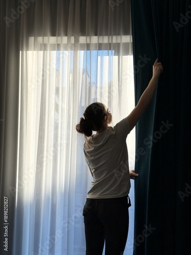 Billede på lærred Housekeeper closing curtains while preparing hotel room for guests